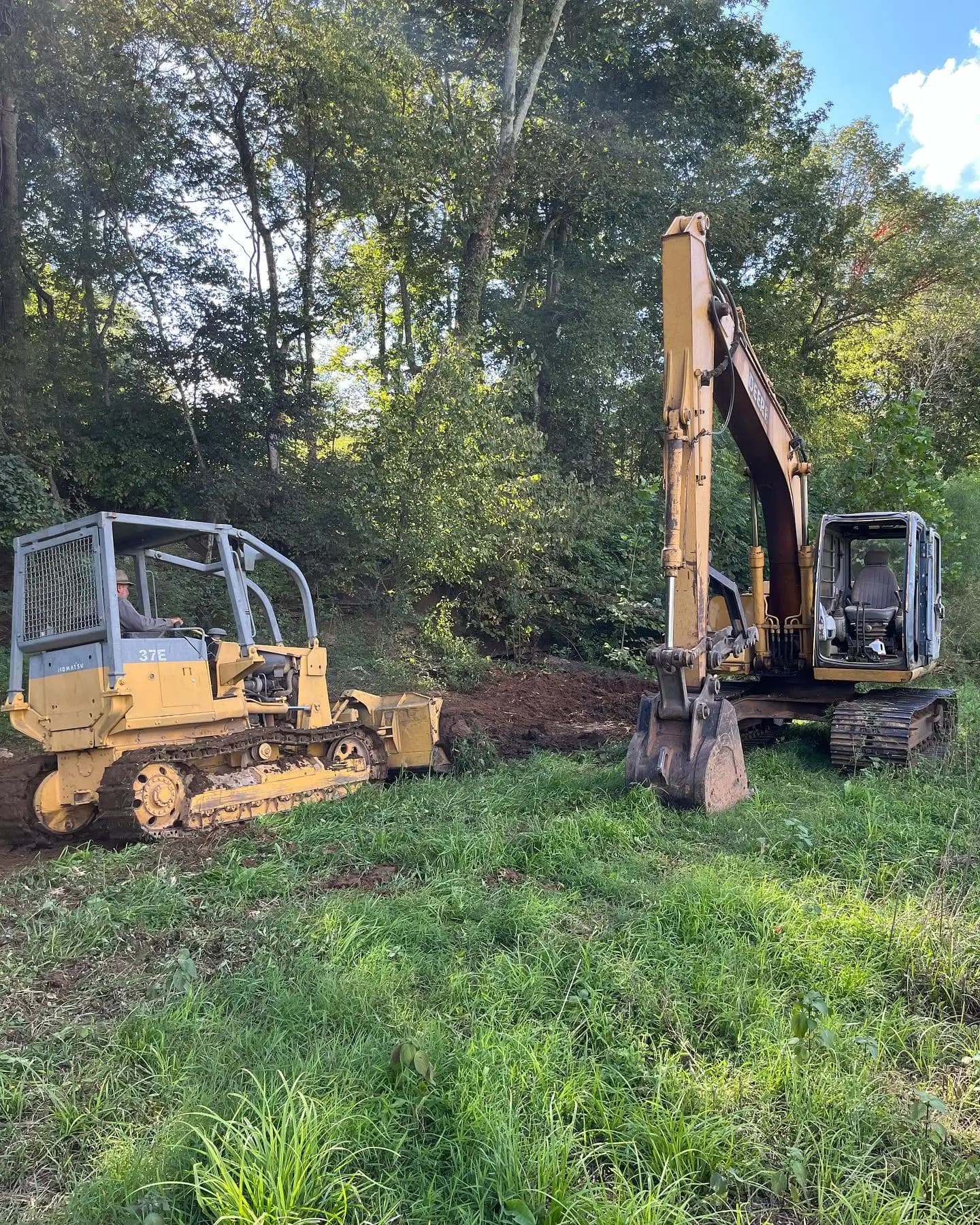 Dozer and excavator clearing a wooded hillside