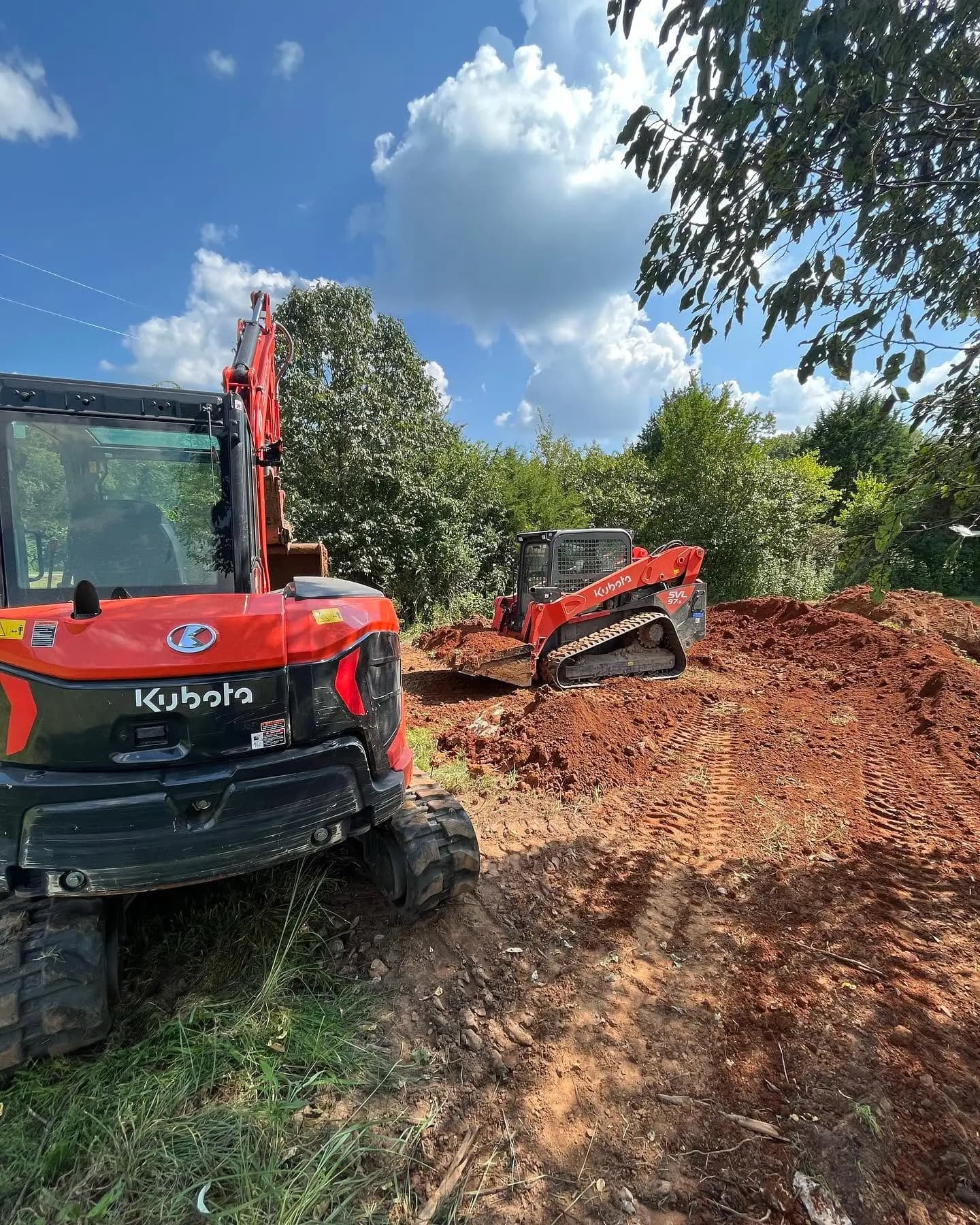 Kubota excavator and track loader moving red dirt on a building site